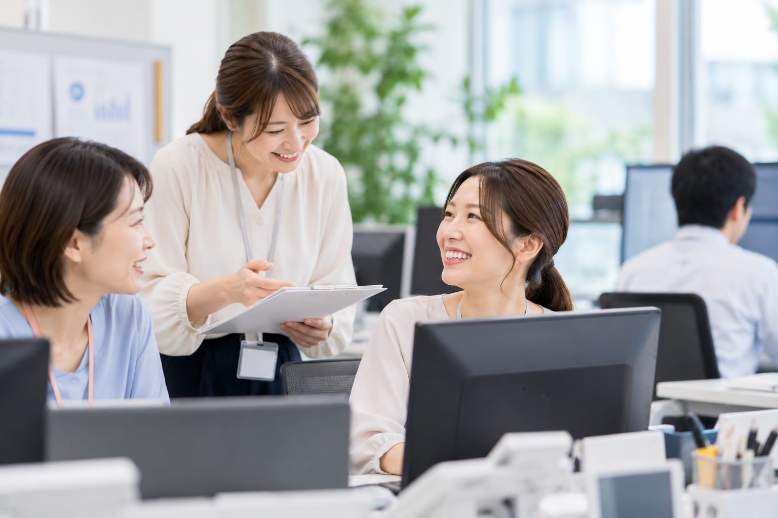 職場で資料を見ながら、笑顔で話すスタッフたち
